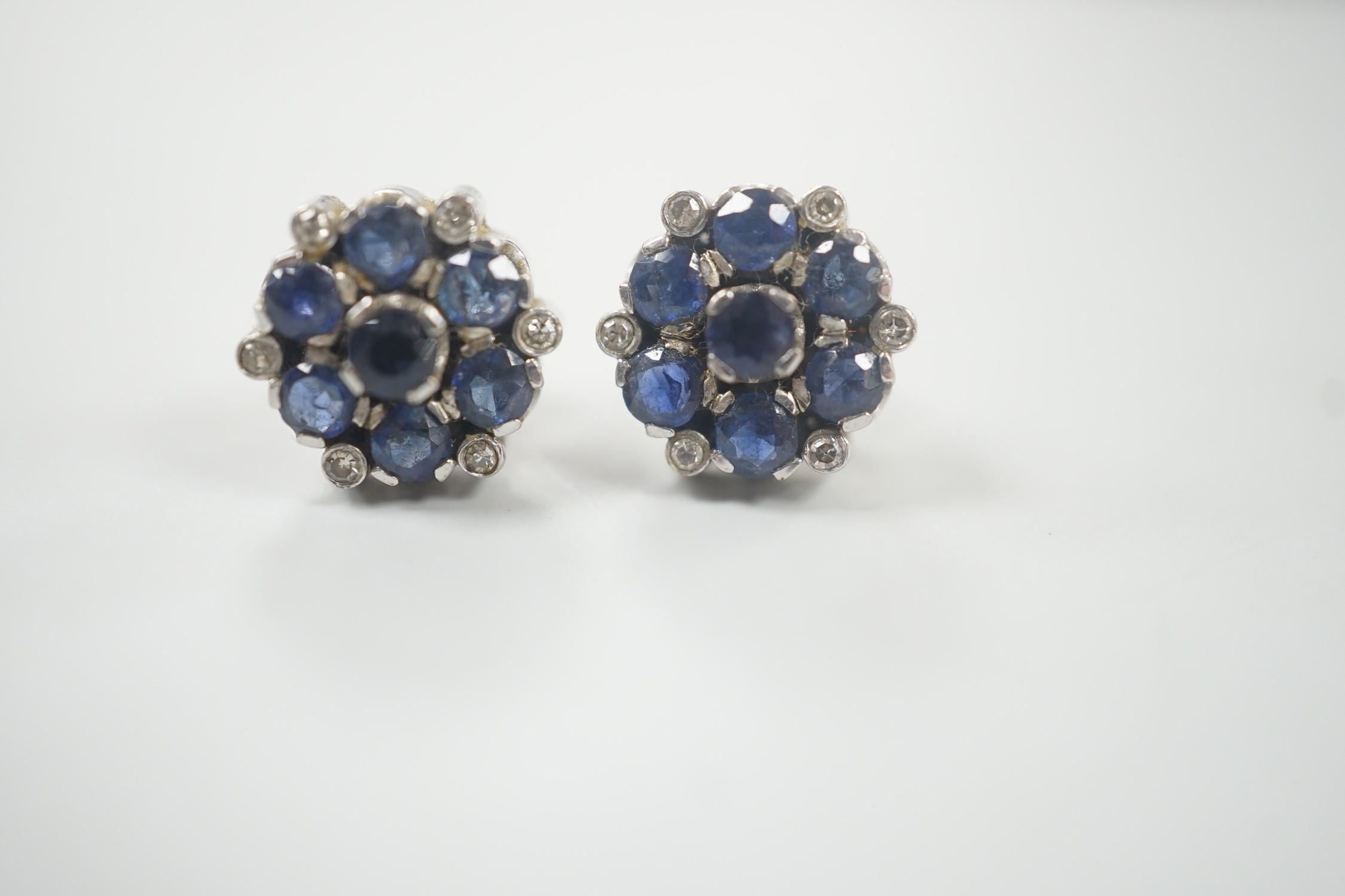 A pair of white metal, sapphire and diamond cluster set flower head ear studs, 10mm, gross weight 4.6 grams.